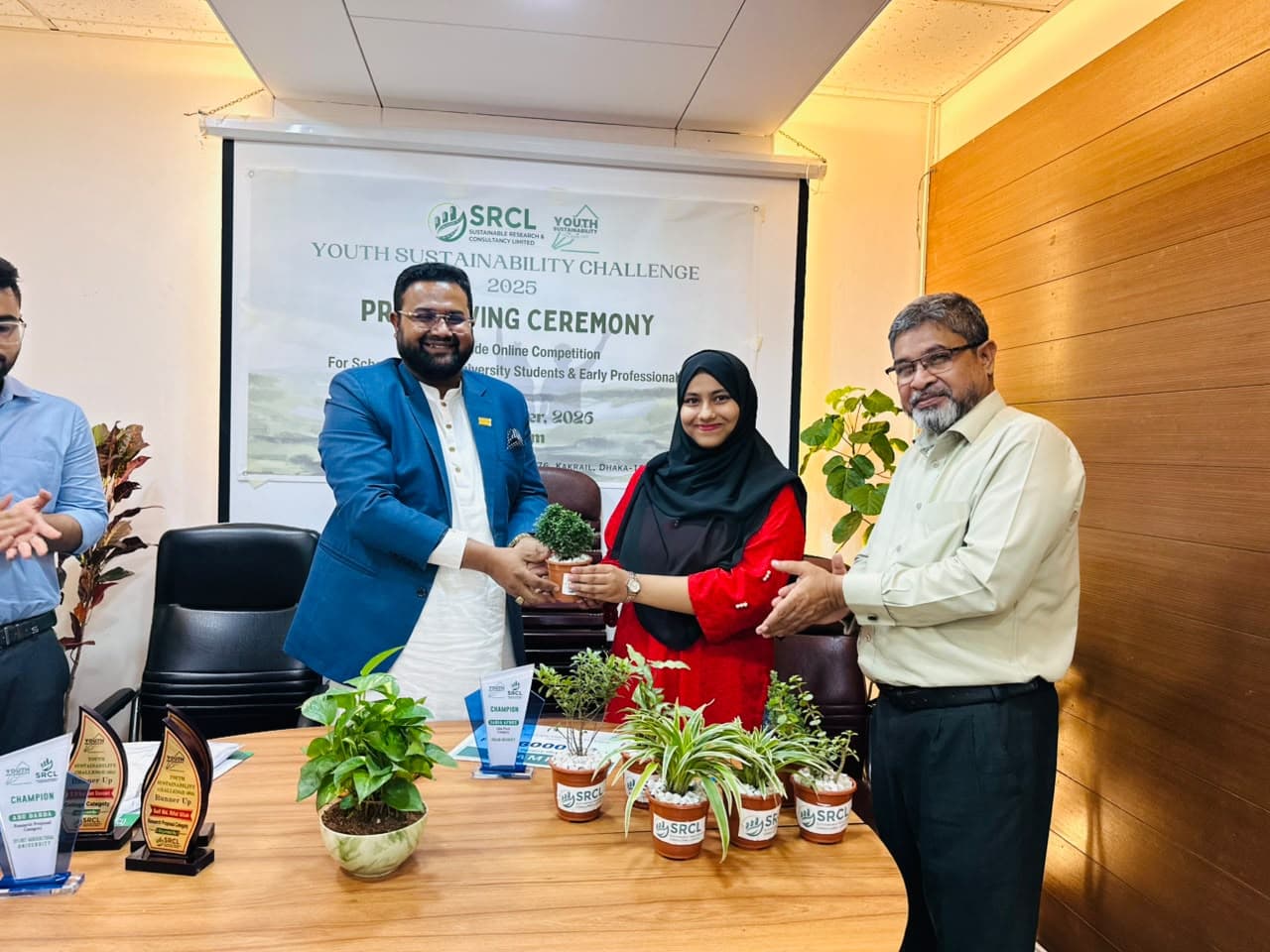 Md. Abu Jubayer presenting a potted plant to a participant during the Youth Sustainability Challenge ceremony